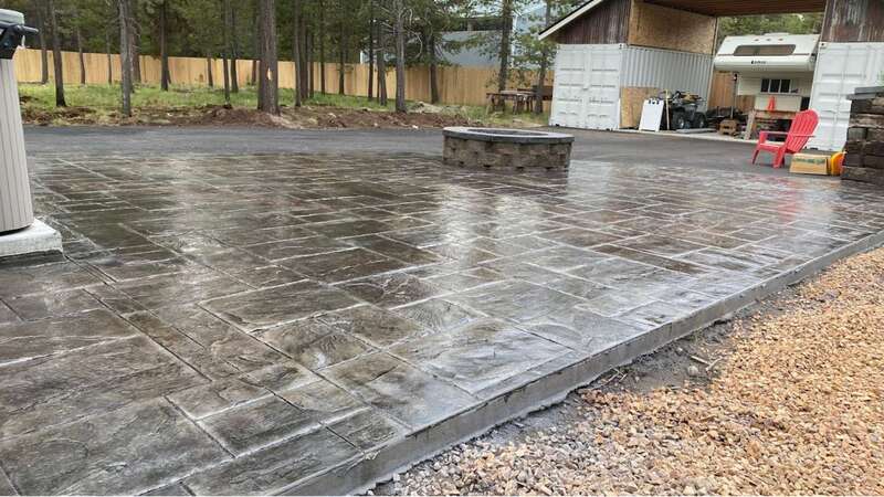 Stamped concrete patio with an outdoor fire pit in a wooded backyard